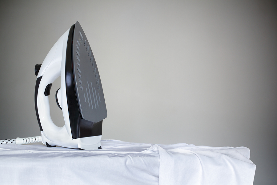 Ironing a white shirt with a steam iron on an ironing board