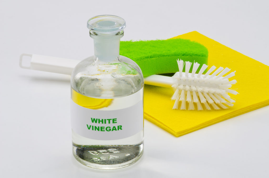 White vinegar in a glass bottle. White background. Organic cleaner.